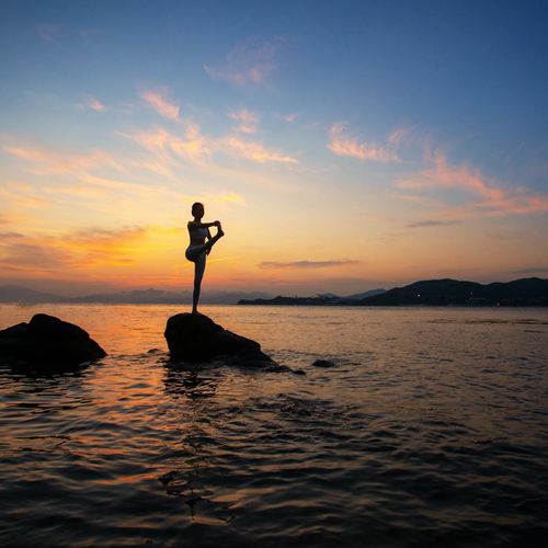 Silhouette of a person in a powerful yoga pose at sunrise.