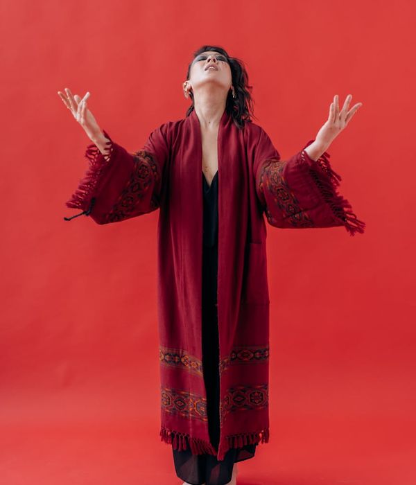 Woman in a balanced yoga pose against a solid background.